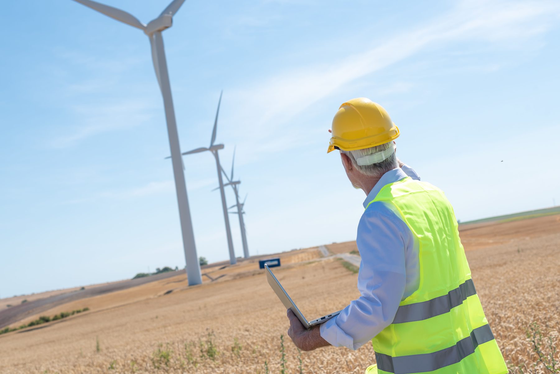 Techniker bei der Inspektion einer Windkraftanlage mit Laptop